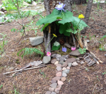 Faerie house in the woods made of twigs, leaves, stones, and flowers.