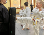 Young children in white gi kicking boards.