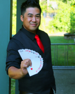Magician Norman Ng holding a fanned out hand of cards.