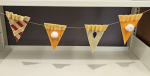 Four felt slices of pie strung across a book shelf.