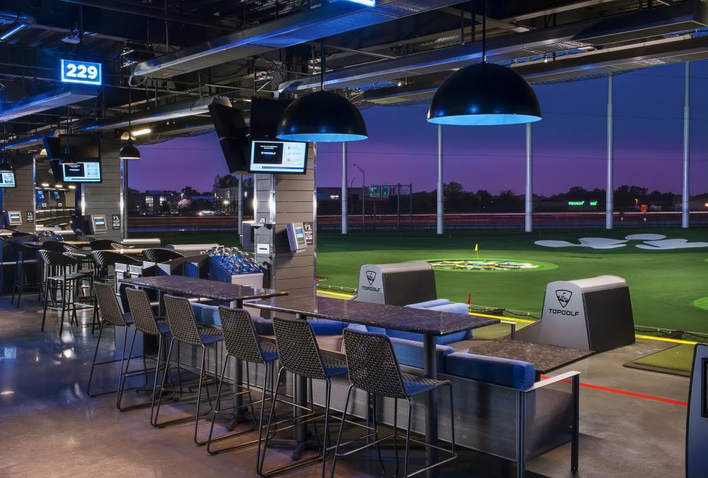 A Topgolf hitting bay at dusk overlooking the lit target greens