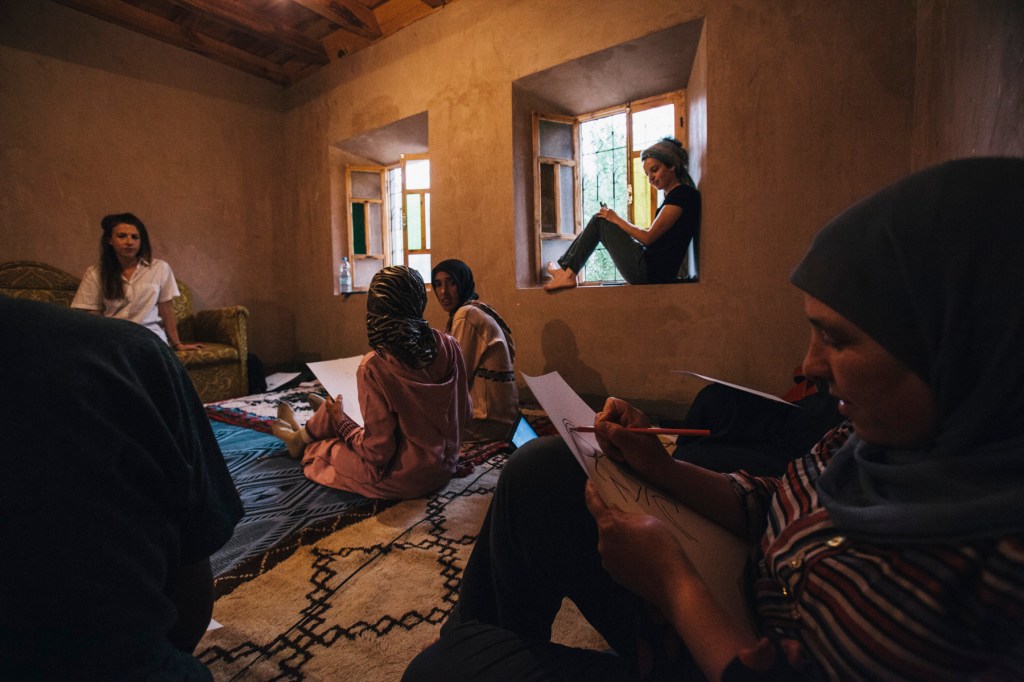 Later on, Sabrina taught the artisans in new design techniques that involved tracing the outline of objects and environments while not looking at the canvas. Here, Sabrina poses so artisans can trace her using this new technique. 
