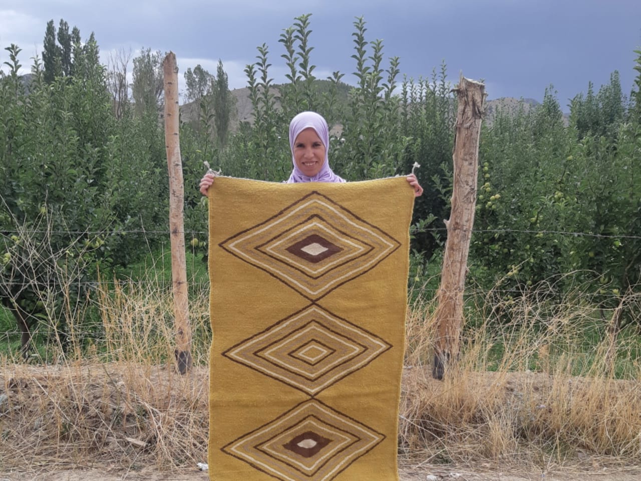 Aicha Termoun of Cooperative Tatrout holding the finished blanket