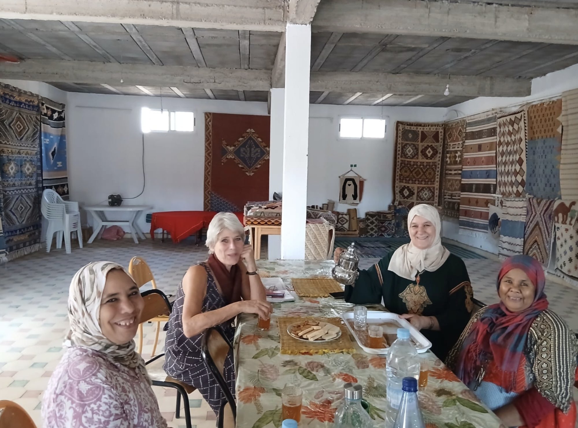 Mieke sharing tea with the women of Afous GAfous in the cooperative's workshop, its walls hung with rugs