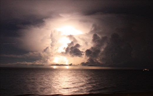 Lightning strikes out in the ocean late at night.  