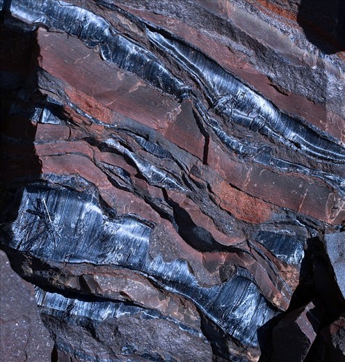 The soft, fibrous Blue Asbestos (Crocidolite) veins embedded in the surrounding hard, iron rich rock