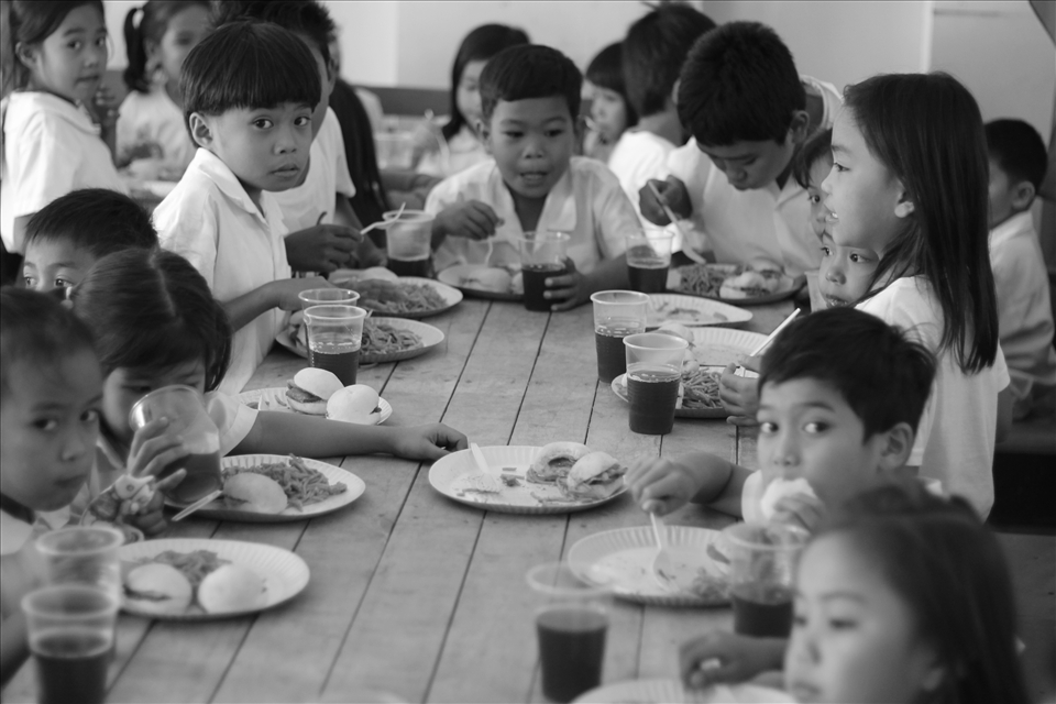 The students eating as a family with the food bring by the group.
