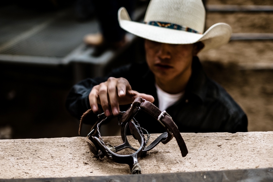 A competitor in the saddle bronc event reaches for his spurs as his time to master those 8 seconds on a frenzied bronc draws near.