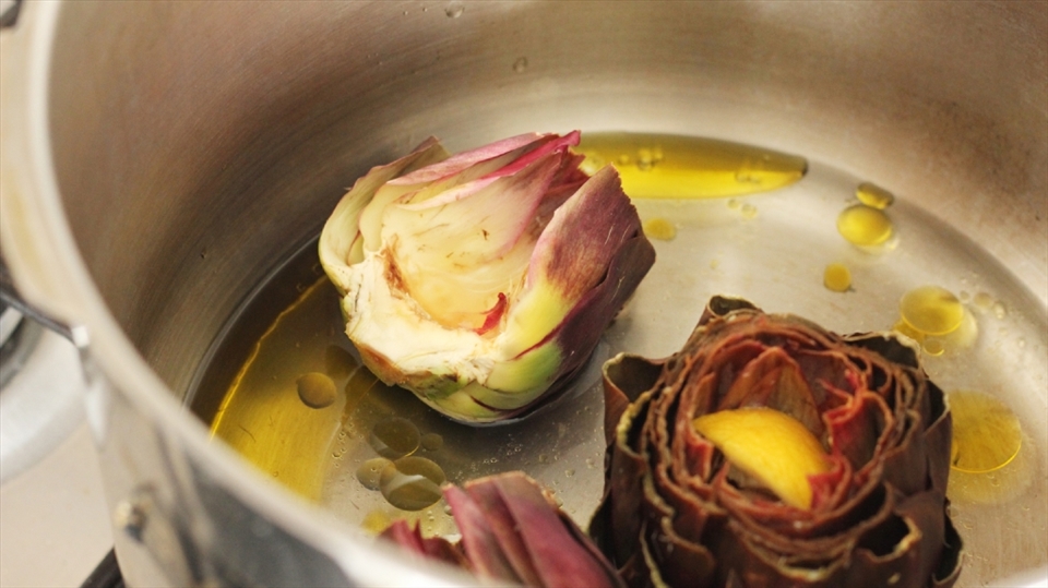 Artichokes trimmed and placed in a pot of lemon juice, olive oil, salt and water.