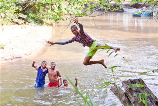 Teenagers play in the river to cool off on their way home