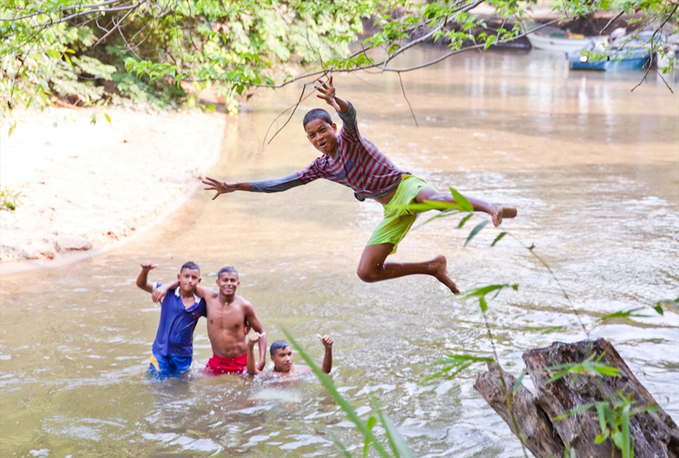 Teenagers play in the river to cool off on their way home