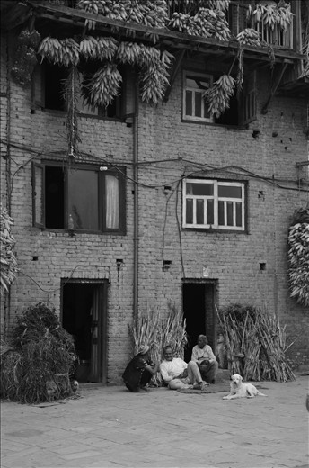 Village life - neighbours catching up surrounded by drying corn and chillies 