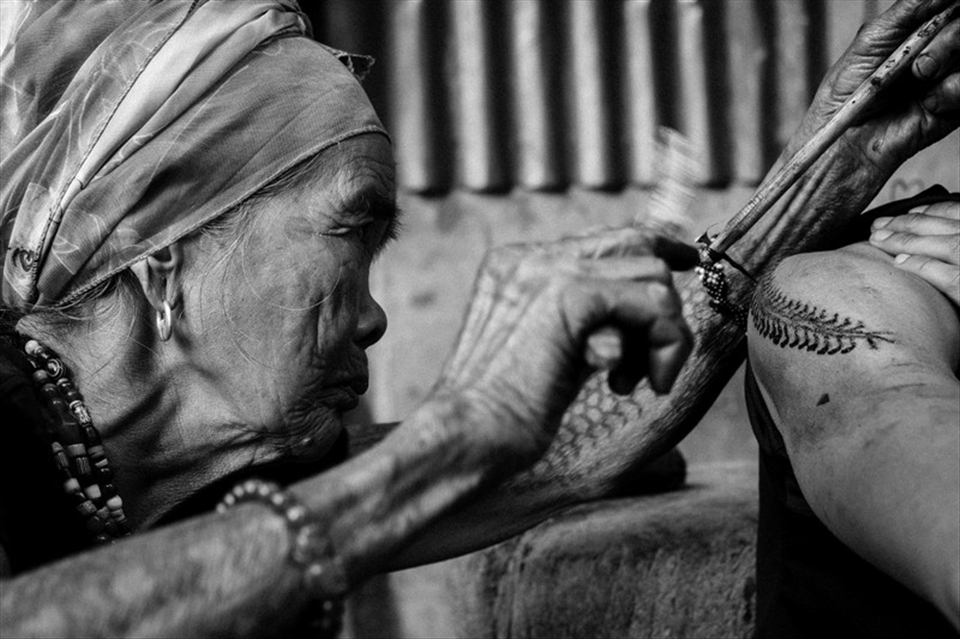 Fang-od while tattooing. Her arm is cover with full sleeve traditional