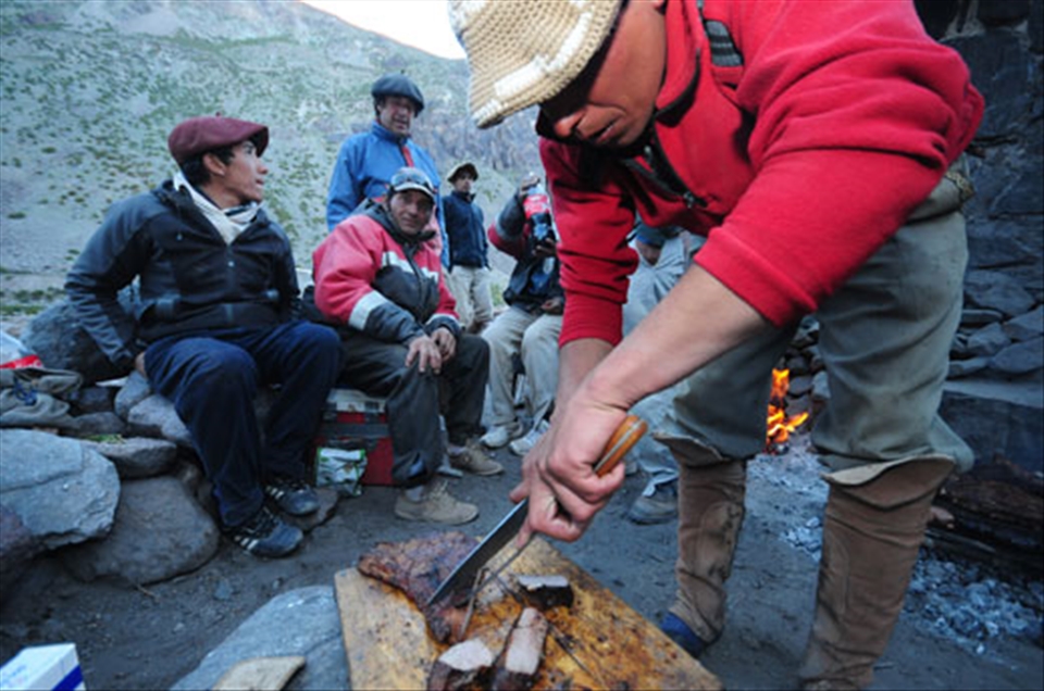 Arrieros feast on a meal of steaks and grilled meat