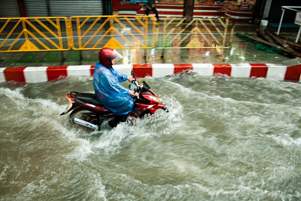 When flash floods hit during monsoon season it's business as usual, armed with nothing but a waterproof poncho this man navigates the newly formed canals of Bangkok on his moped.