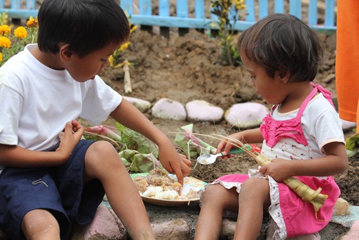 A plate for two. The older brother shares his food to his sister during a feedin