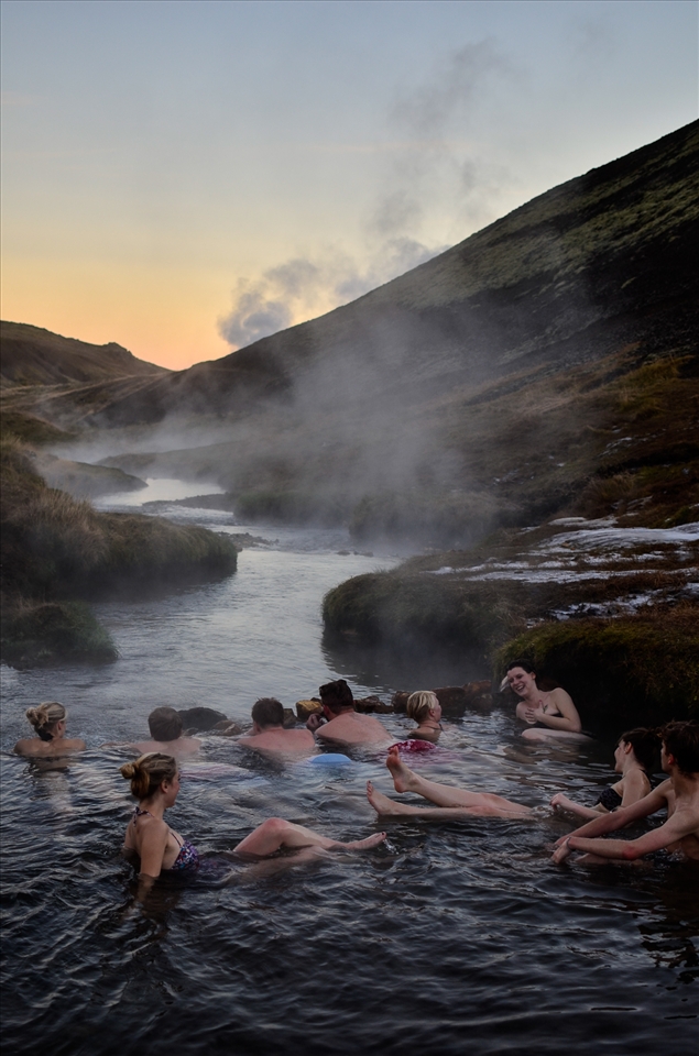 Hikers take a break to bathe in a natural hot river near Hveragerði, Iceland.