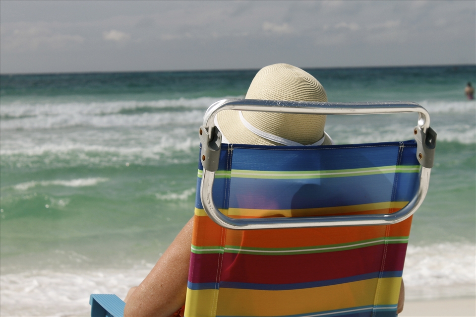 A woman relaxes near the crystal water in quintessential polyester stripes.