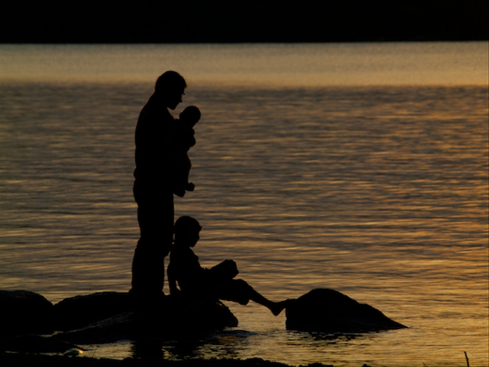 A father enjoys a sunset with his children from the shore of Clearwater Lake.