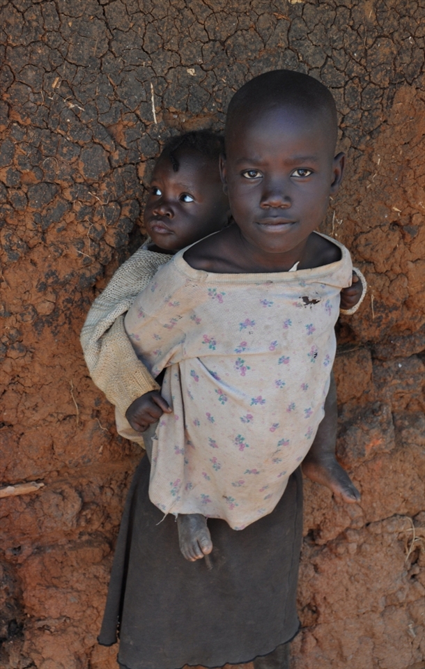 In Kenya's rural Nyanza region  >40% of the population are children <15 years old.Many of thm,mostly girls,act as caregivers to younger siblings.These young caregivers,carrying adult responsibilities,miss the opportunity of a carefree childhood. The photo children are orphans-Hope,aged 8 and her baby sister Faith.Hope took on motherhood tasks after their parents' loss.Faith accompanies her,clinging to her back, in every activity she performs i.e. household chores or fun time.