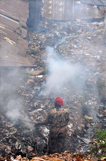 The woman tires to 'recycle' the dump by burning it but this pollutes the air.