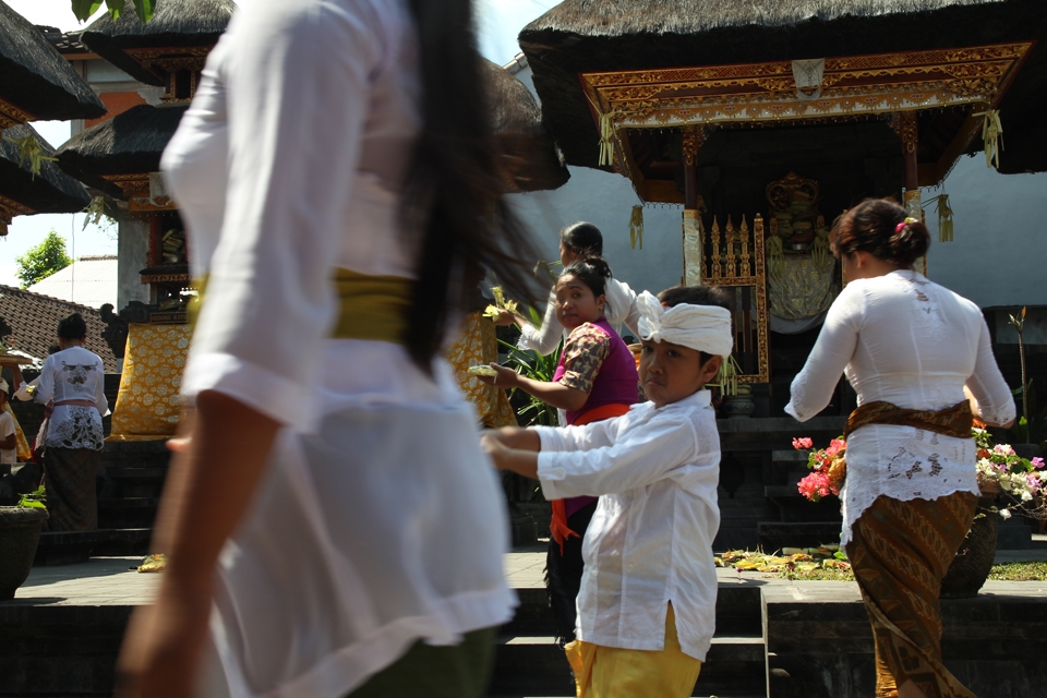 Numerous festivities are held throughout the year involving family members of all ages. This shot conveys the hastiness in one of the temples in Kuta on Galungan. Gifts are being laid in traditional fancy costumes wore on that occasion. 