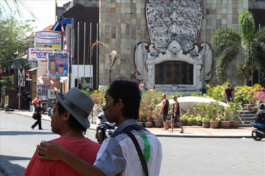 10 years after. Two embracing men, in the background memorial of the bombings in Kuta, Bali, where 202 people were killed during a party night in a club which use to stand in its place. The bombers allegedly targeted alcohol consumption and promiscuity of the party crowd.    
