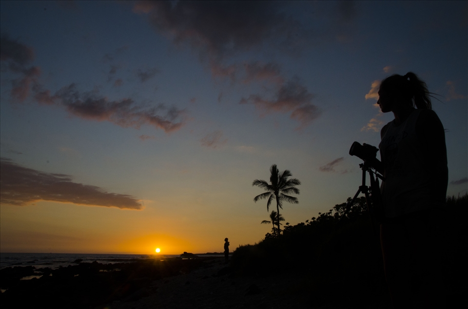 As another day comes to an end in Kona Town locals stop to watch the colors play upon the sky as the sun sets into the ocean.