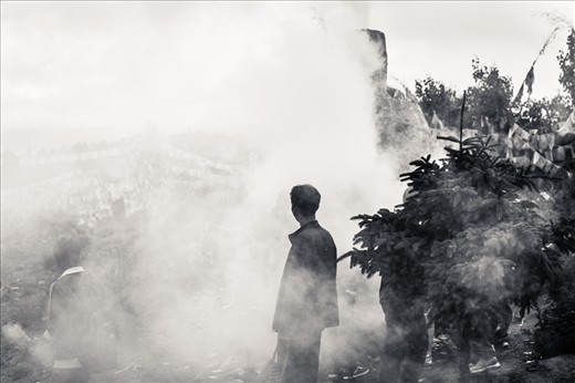 A man is standing out of the smoke of the incense and juniper leaves