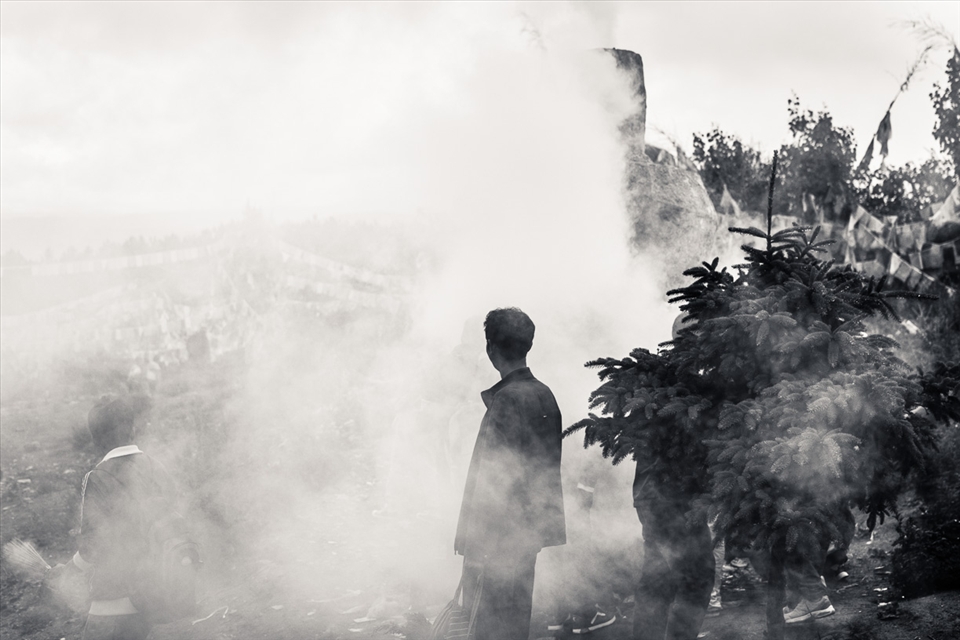 A man is standing out of the smoke of the incense and juniper leaves