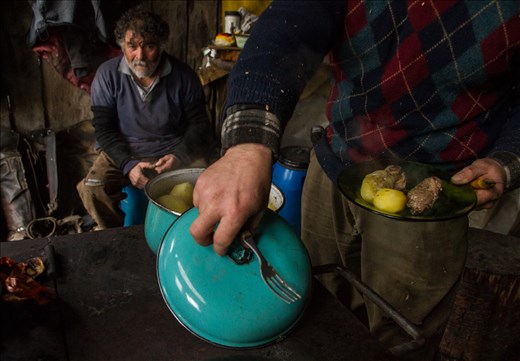 Meat and potatoes, a Patagonia staple of ranch life seen here on a plate, juxtaposed between the colorful lid of an old pot and the ranch laborers about to eat lunch.