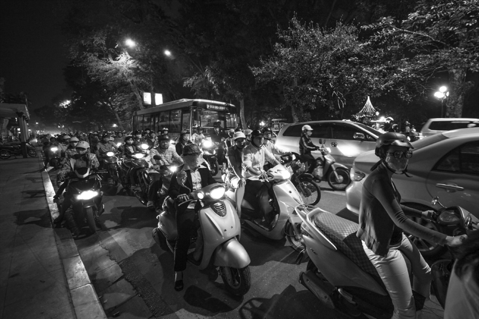 Commuters wait while the traffic light turns green. 
