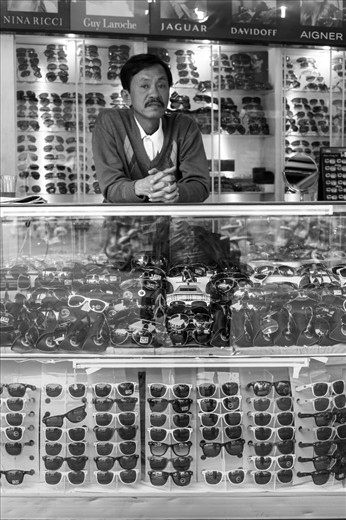 A Vietnamese man waits for a sale at his sunglass shop