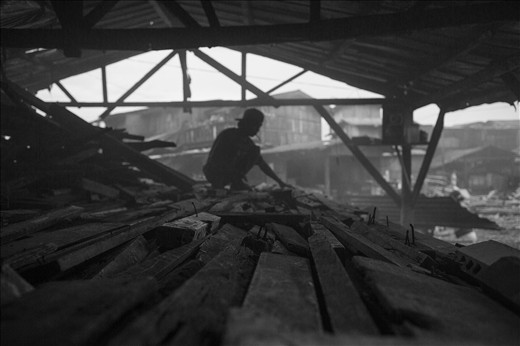 This worker, in his early age, tries to sort the stockpile of woods, covered wit