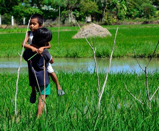 These two kids are from our barangay and they are motherless already. Big sister carrying her little brother who is sick and making sure his feet not get wet .