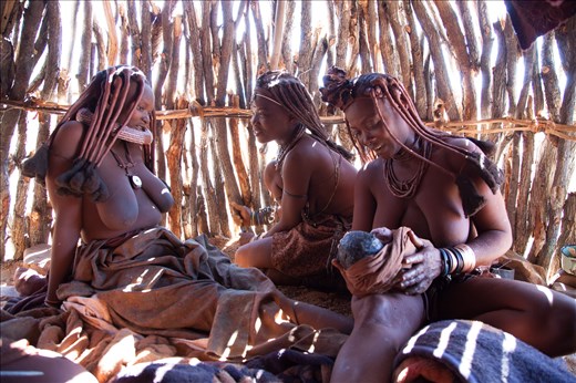 A moment of joy shared by Menjamwapi, her mother and sister after the successful birth. The whole family will share the responsibility of raising the baby. This family unit lives with no men. Both sisters are unmarried which becomes a common phenomena with the Himba as men are drawn to cities. Women often find themselves responsible for all aspects of life.