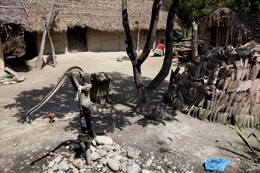 A woman is making natural fertilizer in front of her traditional mud house.