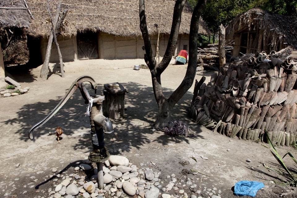 A woman is making natural fertilizer in front of her traditional mud house.