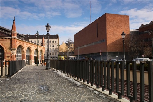 The beautiful old marketplace, Budapest, across a strange brick structure and large metal fence.