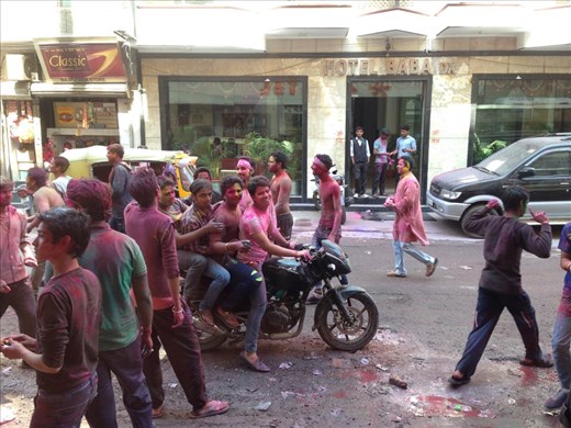Motorbike with 4 people on it playing Holi