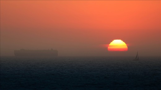 A cargo ship and sailboat enjoy the last little bit of light for the day