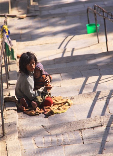 The stairway to the Stupa sits two brave girls, their eyes filled with hope.