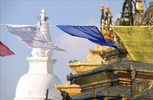 A thousand buddhist prayer flags move with the wind, surrounding the Stupa.