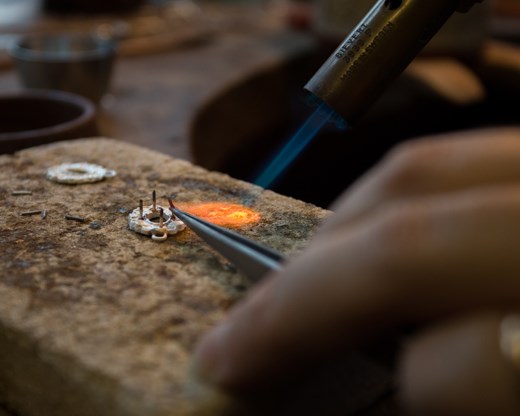 Moira heats the enamel and metal so she can build up her design