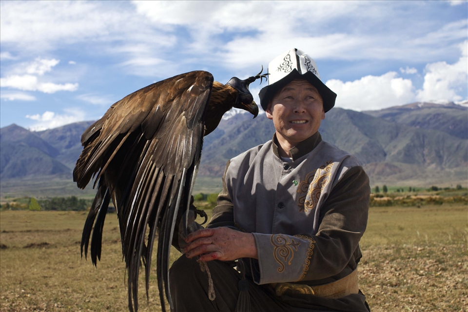 Man holds eagle in apprehension of releasing the blinders.