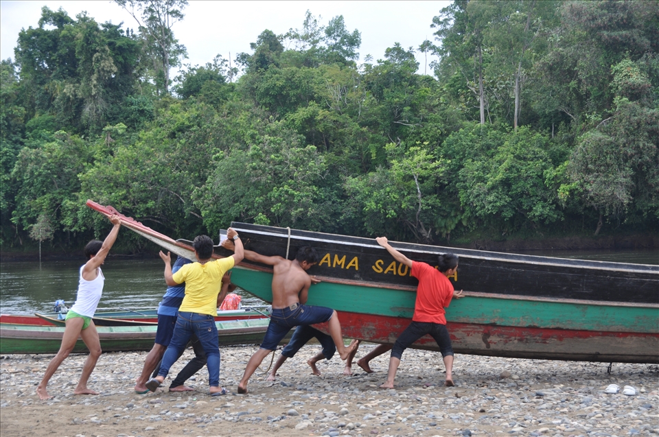 Team Work, some men are pushing the boat because the river was recede.