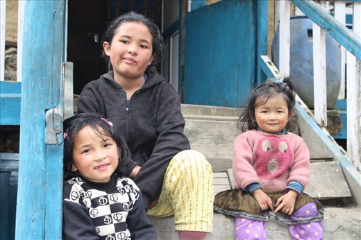 04.Little Sherpa Smiles: 
Wonderful 3 little Sherpa sisters sitting at their door steps with two genuine smiles and one confused look. A common scene during the trek on the route which is commonly blended by the local greeting: “Namaste”.
