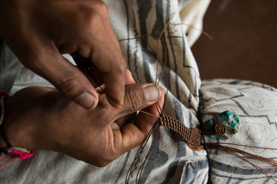 A Peruvian weaves a necklace to be sold at an artisan craft fair 