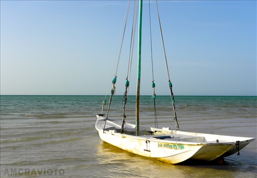 A small boat is stranded on the sand as the tide retreats into the ocean