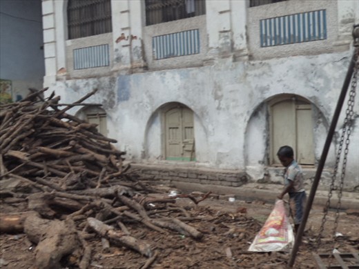 Boy picking up the wood they use to burn the bodies at one of the burning ghats